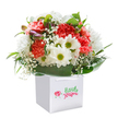 Bursting with sentiment, this vivid bouquet appears like a splash of spring caught amid local Bexleyheath blooms and artistry. Arranged upright in a sleek white gift bag with neat ribbon handles, the display radiates sincere joy, its coral and peach carnations lavishly ruffled and kissed with hints of soft scent, reminiscent of a stroll past the local flower stalls on a sunny day. White daisies, each one boasting a golden-green centre, intermingle playfully with the larger flowers, while airy clouds of gypsophila weave delicately through the bouquet, their miniature blossoms imparting a sense of innocence and lightness. Lush, deep green leaves cradle the blooms, giving form and a natural wrap that reflects the greenery you might encounter in the neighborhood's tranquil gardens or at Danson Park. Peeking through on the left, newly emerging purple-tipped buds suggest hope and new beginnings-subtle and intriguing. Set against a clean white background, every petal and leaf is clearly defined, showcasing freshness and expert arrangement. This bouquet is ideal for marking birthdays, anniversaries, or simply kind gestures, and is a genuine reflection of Bexleyheath's passion for floristry, ready for swift local delivery.